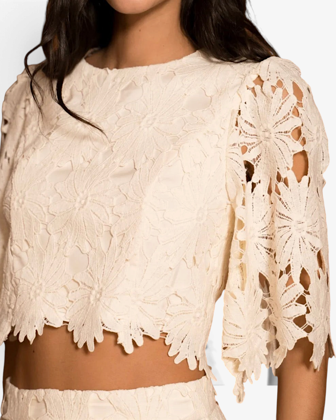 Top court HELLES blanc en dentelle avec motif floral et manches mi-longues porté par une femme