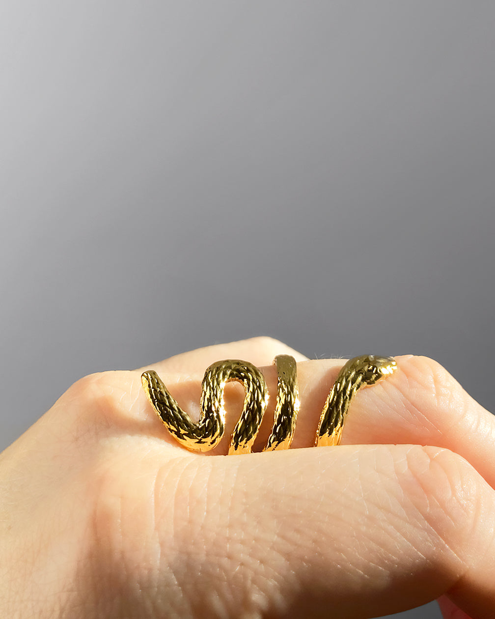 Bague serpent HELLES ajustable en laiton doré à l'or fin 24 carats avec texture écailles sur un doigt