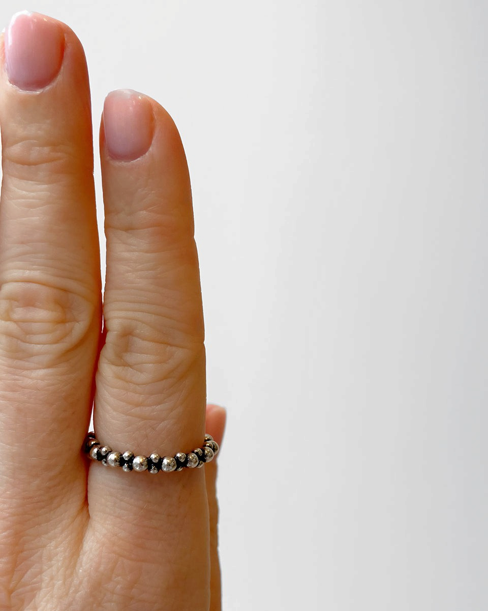 Bague HELLES ajustable en laiton argenté et patiné avec un design de petites perles, portée sur un doigt.