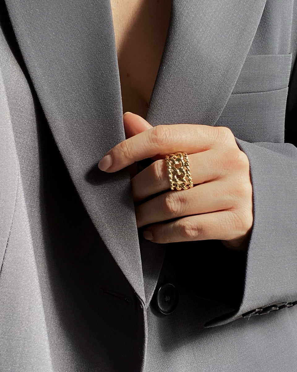 Bague Rock HELLES ajustable en laiton doré à l'or fin 24 carats portée sur un doigt avec un blazer gris