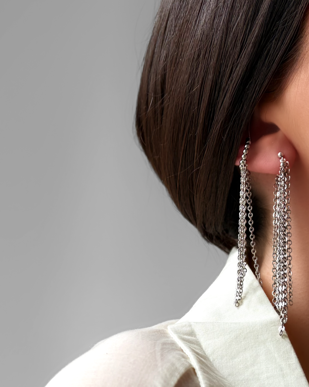 Boucle d'oreille HELLES Duna longue à chaînes multiples en laiton argenté patiné portée à l'oreille