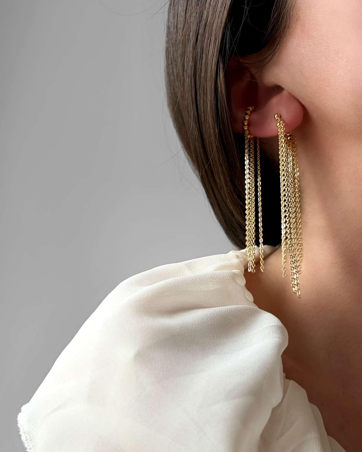 Boucle d'oreille HELLES Duna longue à chaînes pendantes en laiton doré à l'or fin 24 carats portée à l'oreille