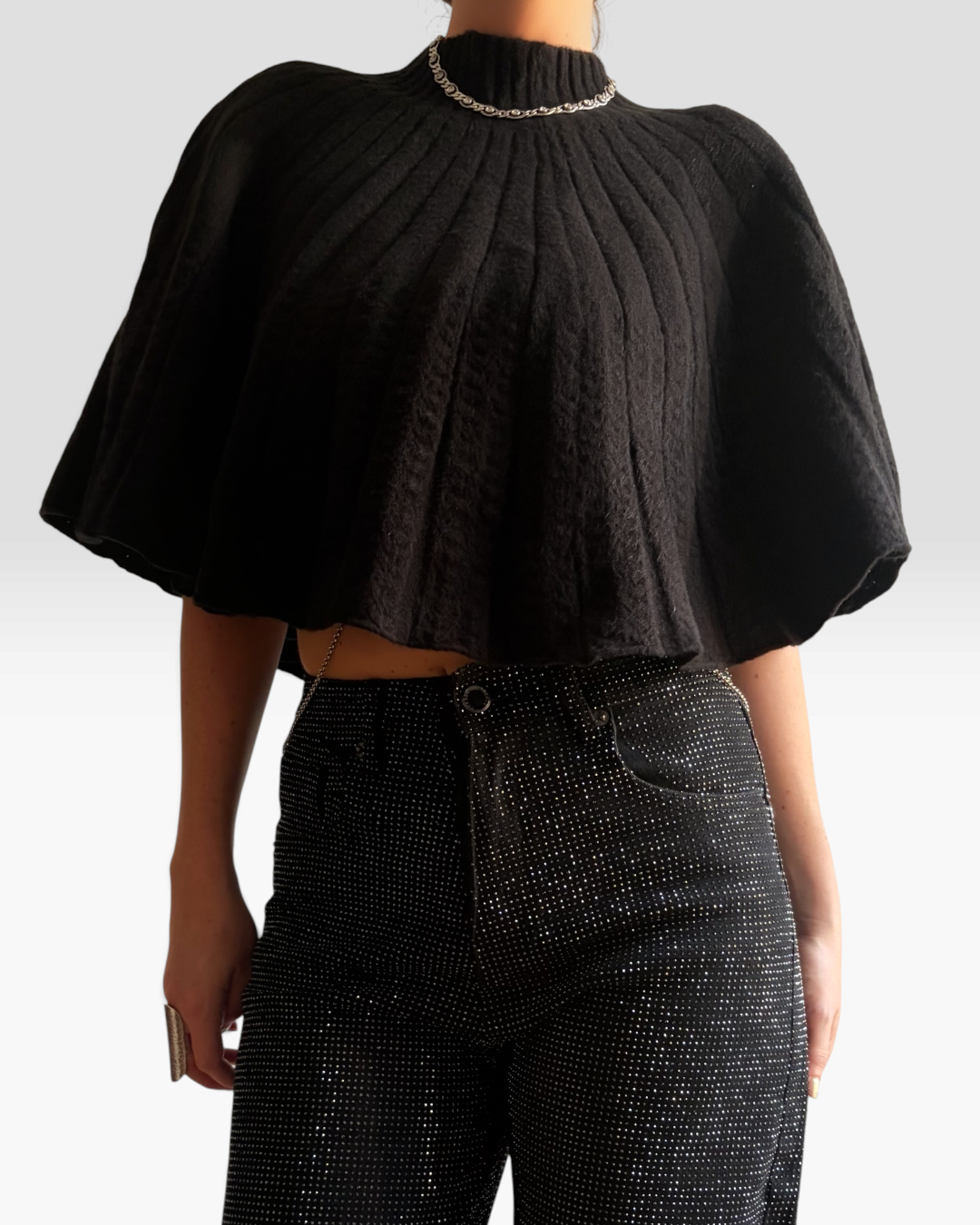 Cape Dolce HELLES noire à col montant et texture côtelée portée avec un pantalon scintillant